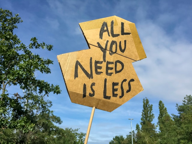 Cardboard sign with the handwritten message “All you need is less,” representing how focused B2B marketing efforts deliver better business results than scattered, unfocused activity.