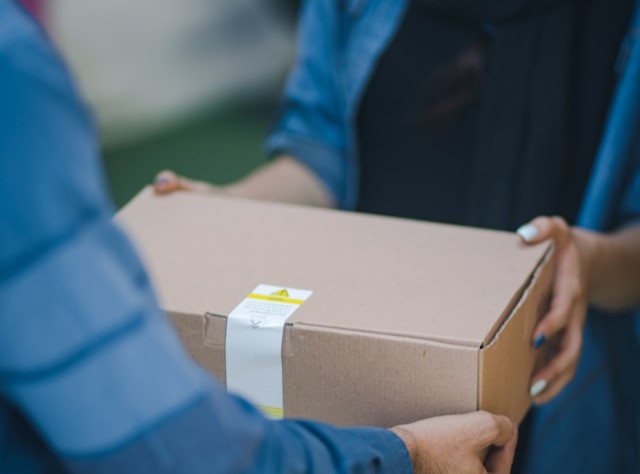 Person handing over a cardboard box, symbolizing delivering results and providing something of value—reflecting how well-built B2B marketing campaigns should support business goals.
